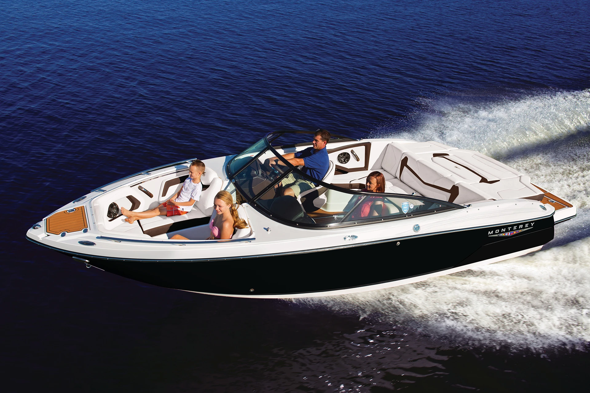 Monterey 238SS sport boat cruising with a family onboard, showcasing spacious seating and sleek black hull