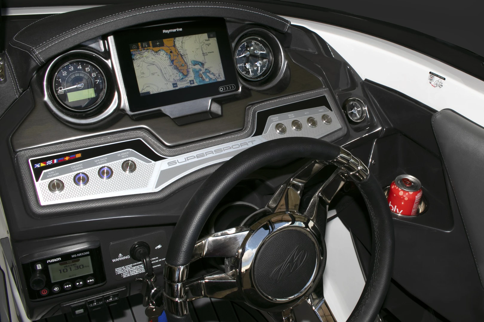 Close-up of the Monterey 238SS helm with Raymarine navigation display, dual gauges, stainless steering wheel, and accessory switches