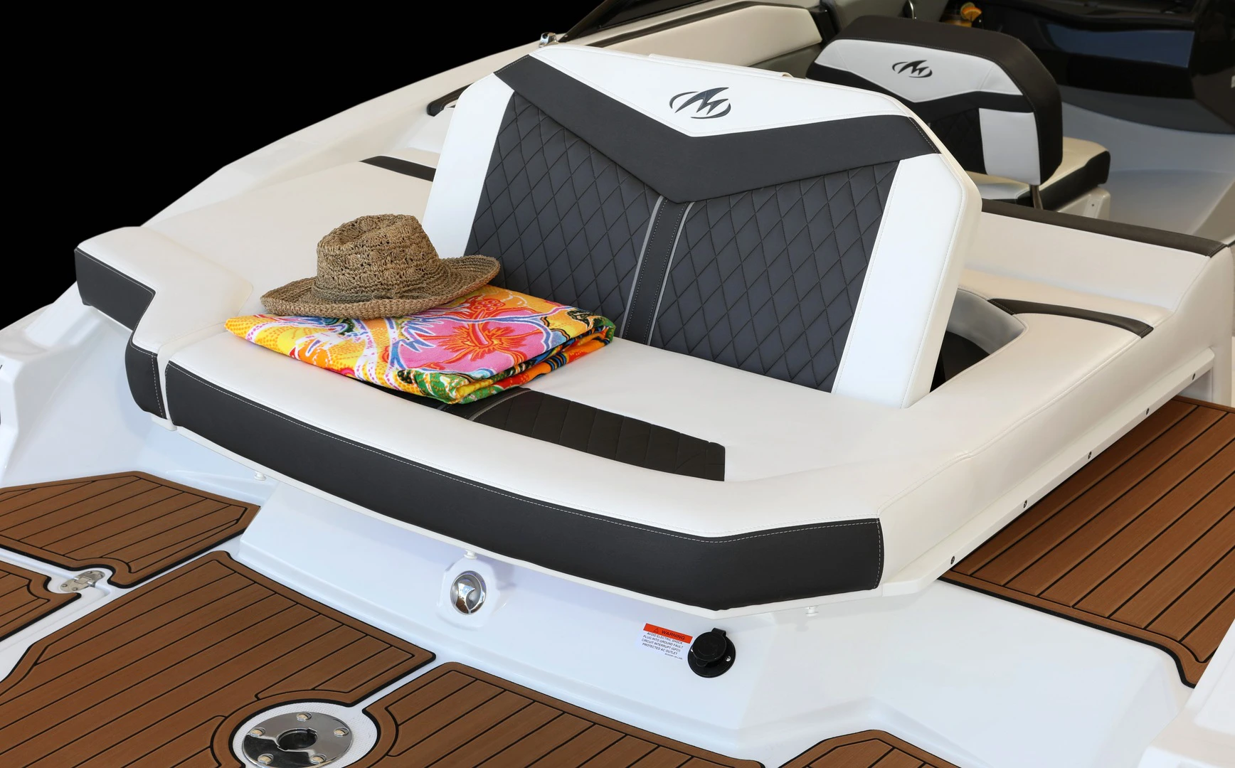 Aft sun lounge with quilted upholstery, hat and towel resting on top, overlooking the extended swim platform