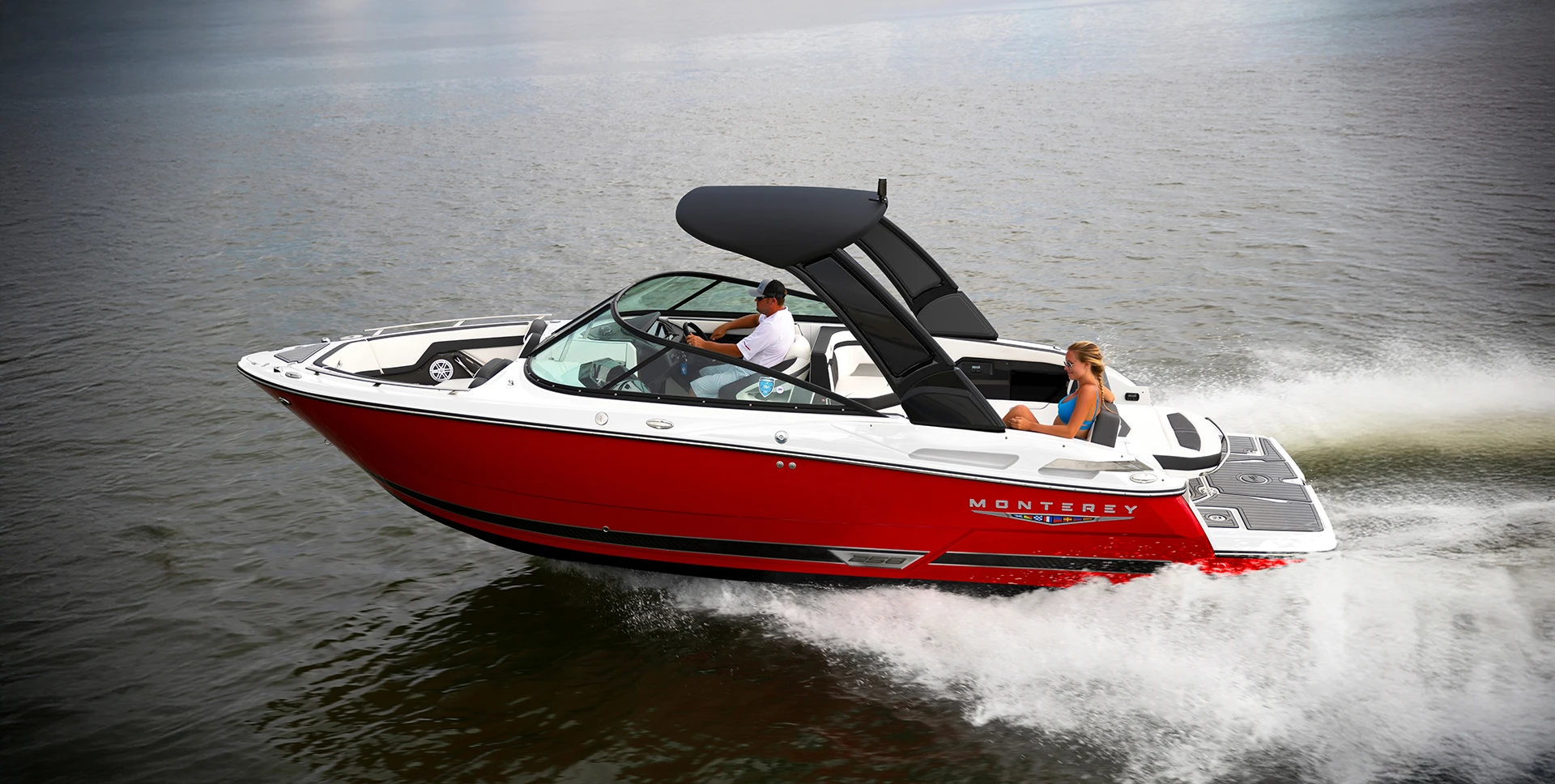 Side view of a red Monterey 258SS speeding across the water with passengers on board
