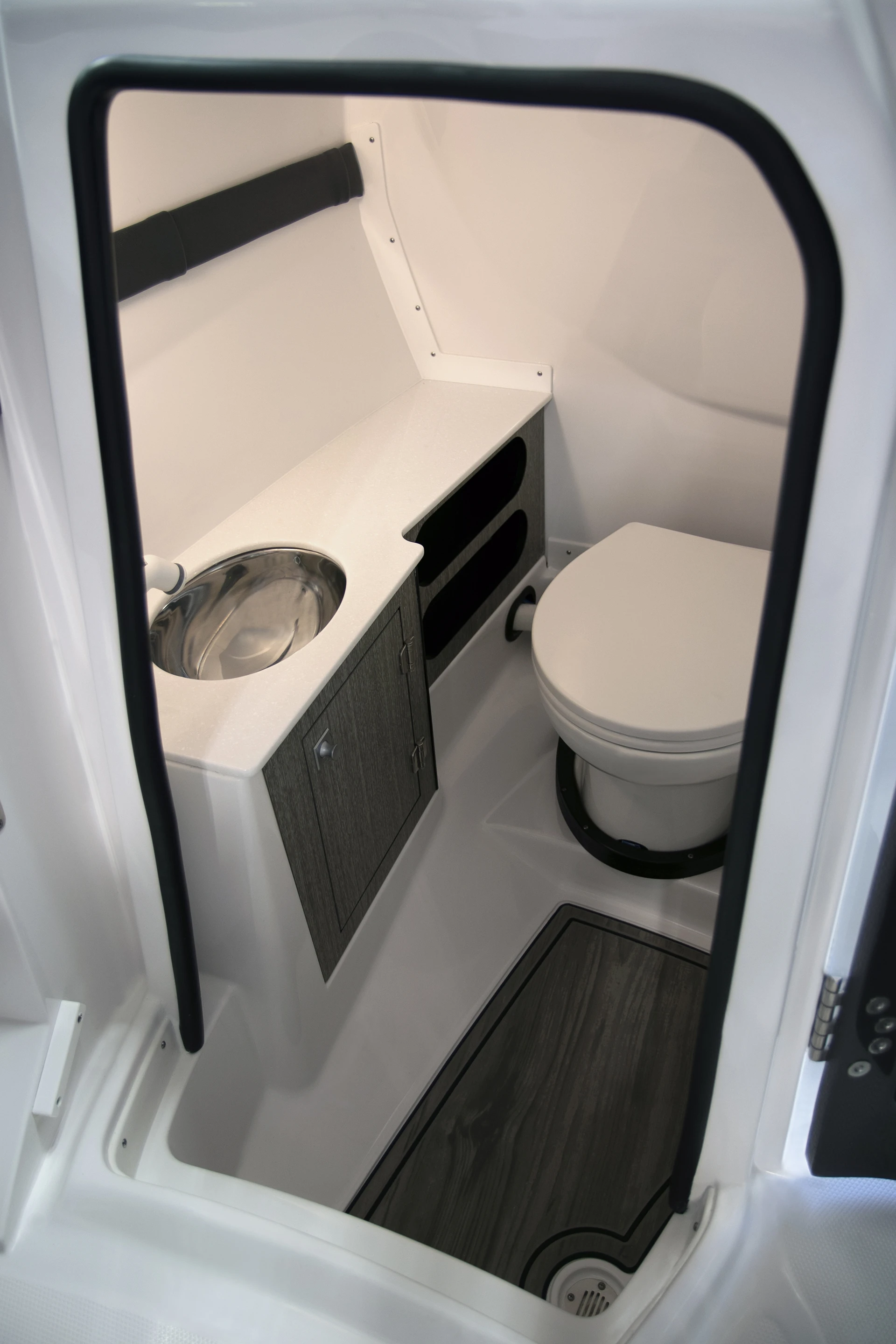 Interior head compartment with china flush toilet, stainless sink, and storage cabinetry