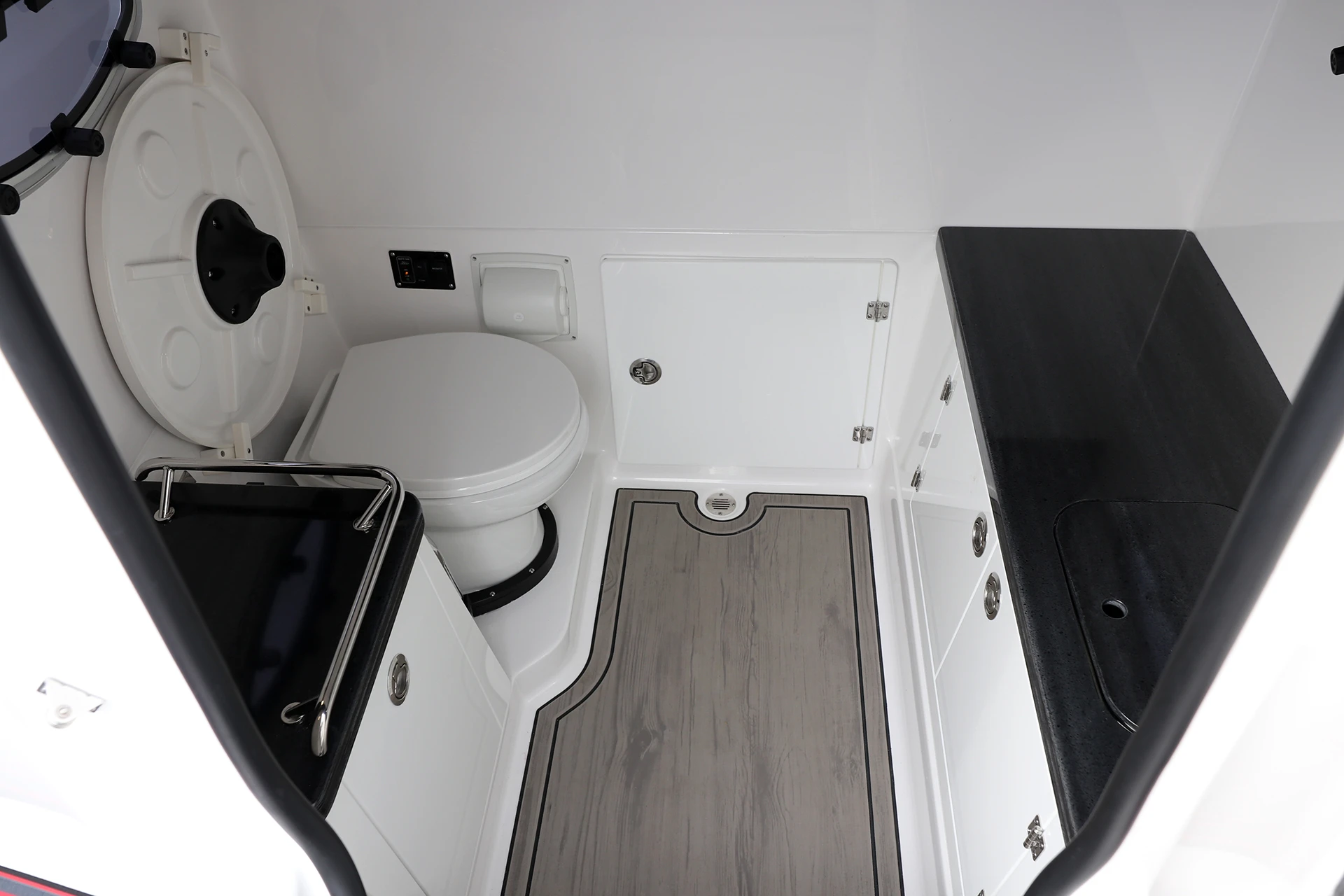 Enclosed head compartment featuring an electric toilet, countertop, and storage cabinetry