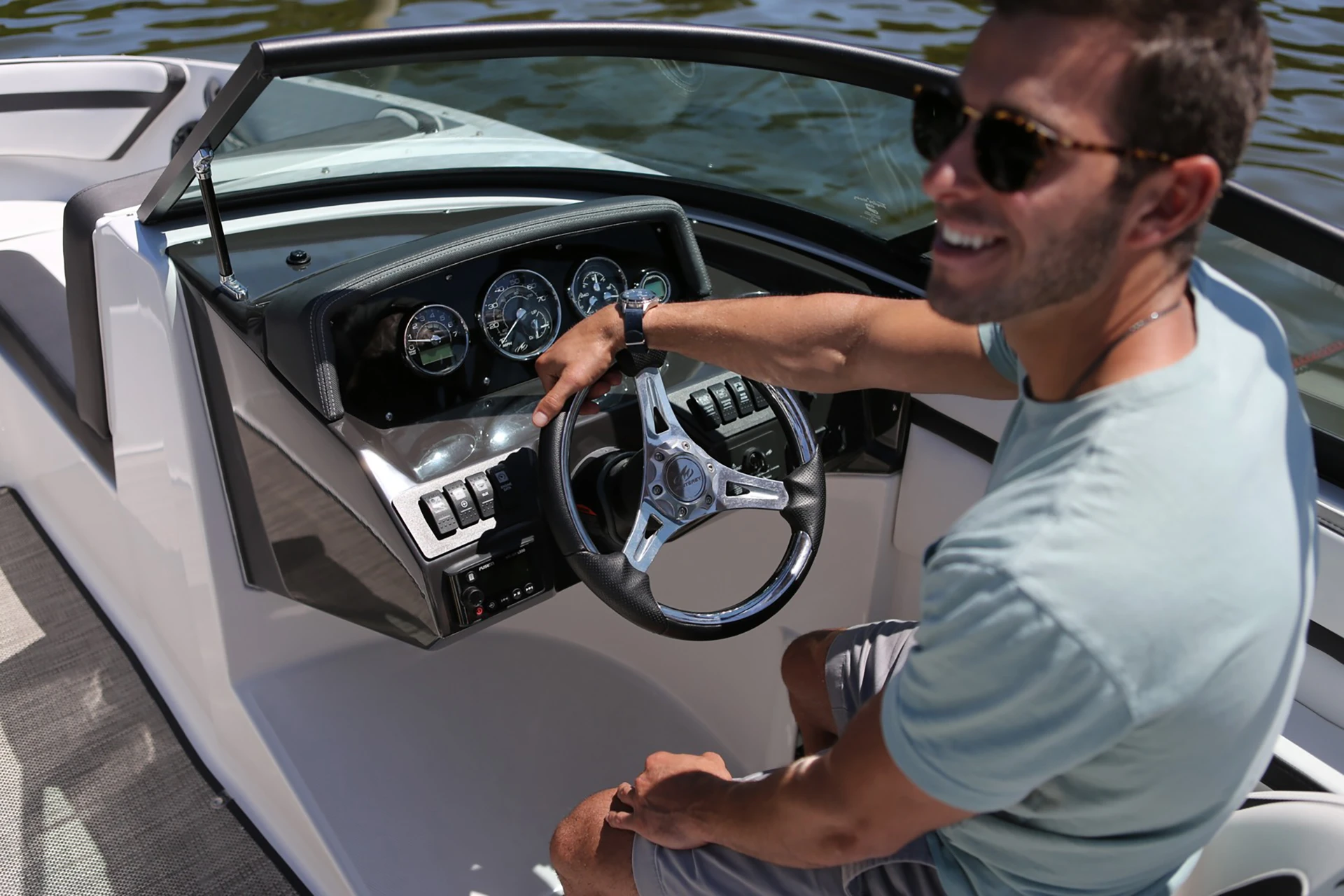 Man at the helm of a Monterey M-205, showing steering wheel and gauge cluster