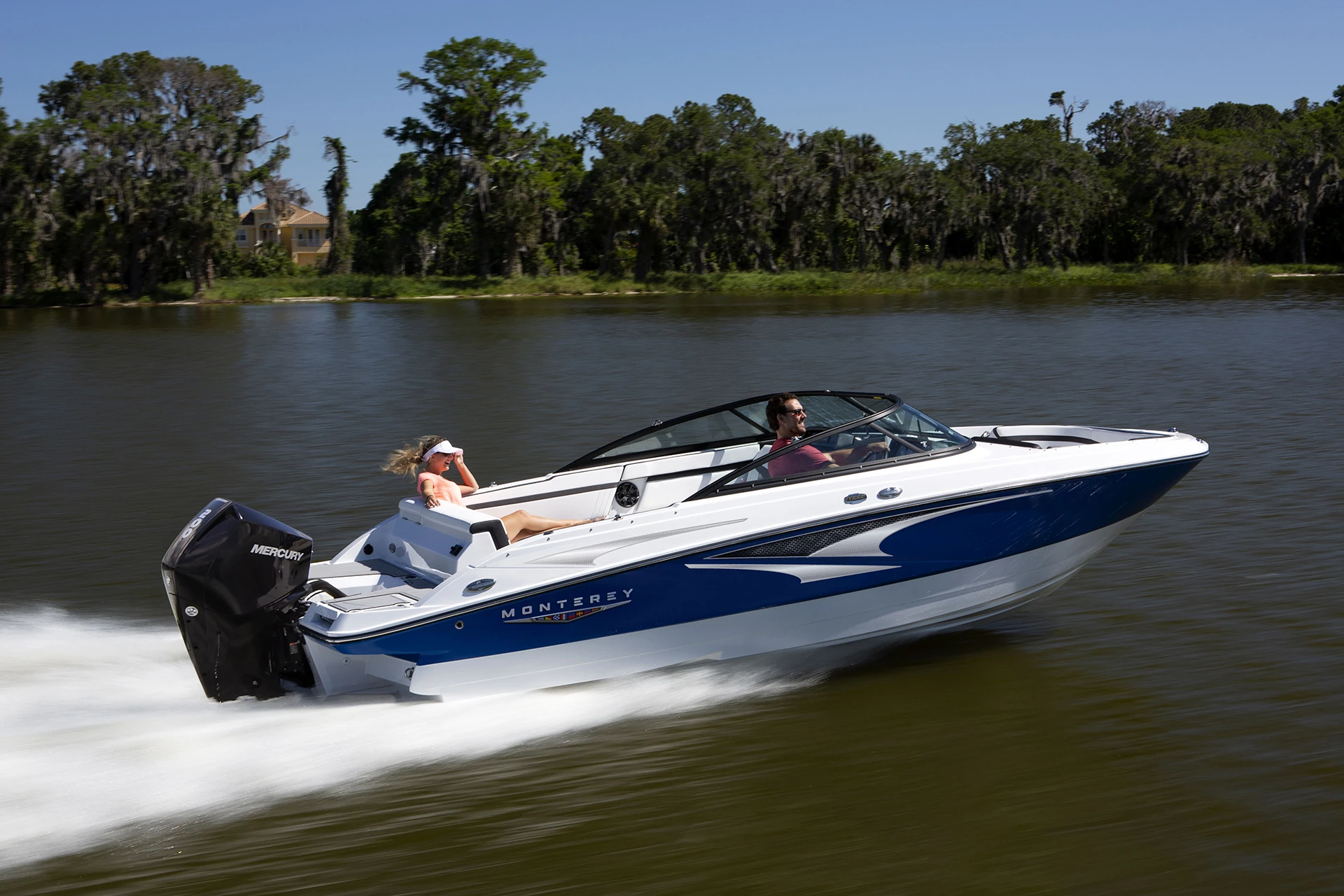Monterey M-225 runabout cruising on the water with Mercury outboard engine and blue hull accent